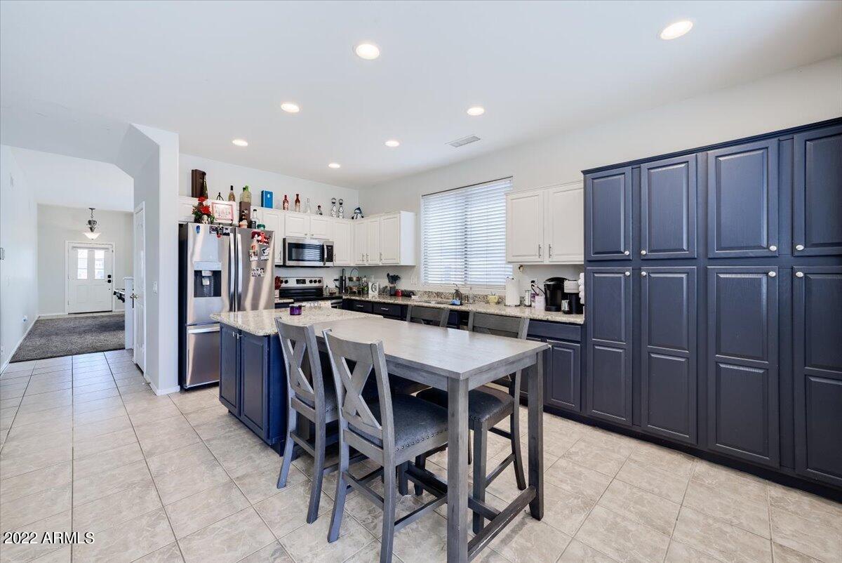 3889 East Timberline Road Gilbert, AZ 85297 - Photo 6 of 25 a kitchen with stainless steel appliances granite countertop wooden cabinets a center island and a refrigerator