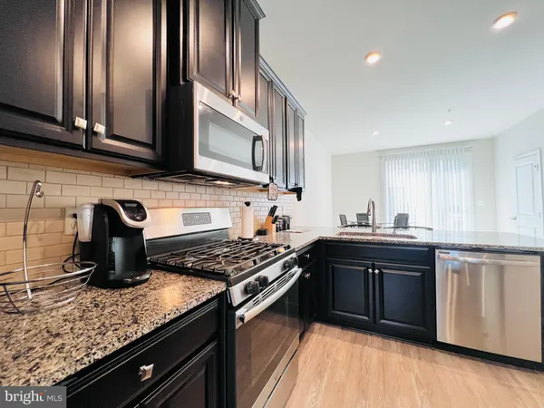 a kitchen with stainless steel appliances granite countertop a sink stove and cabinets