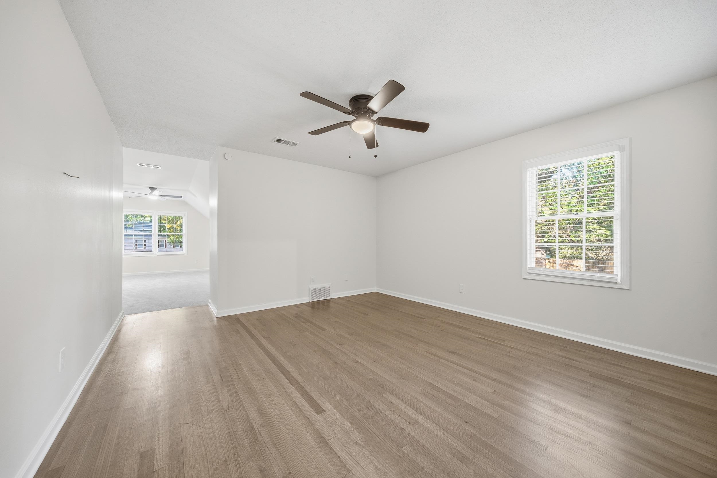 6246 Quince Road Memphis, TN 38119 - Photo 18 of 27 an empty room with wooden floor ceiling fan and windows