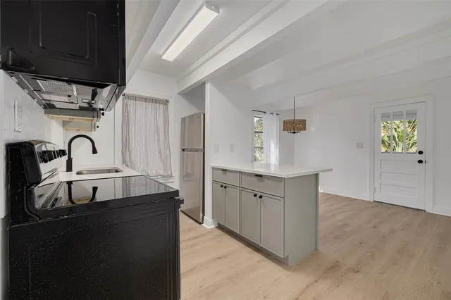 an empty room with wooden floor cabinet and windows