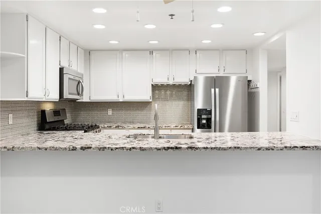 a kitchen with stainless steel appliances granite countertop a sink refrigerator and cabinets