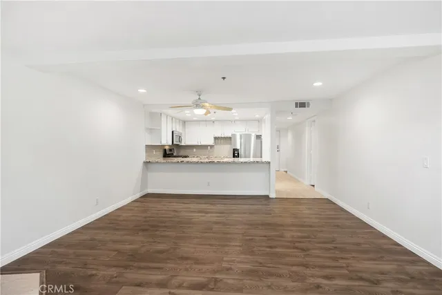 a view of an empty room with wooden floor fireplace and a window