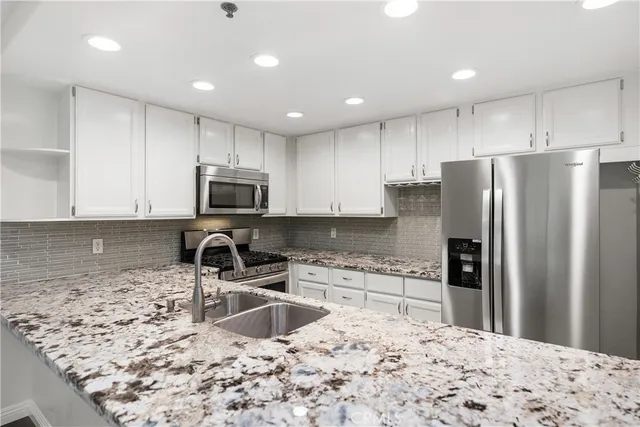 a kitchen with stainless steel appliances granite countertop a refrigerator sink and stove