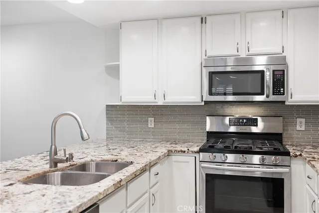 a kitchen with stainless steel appliances granite countertop a sink stove oven and refrigerator