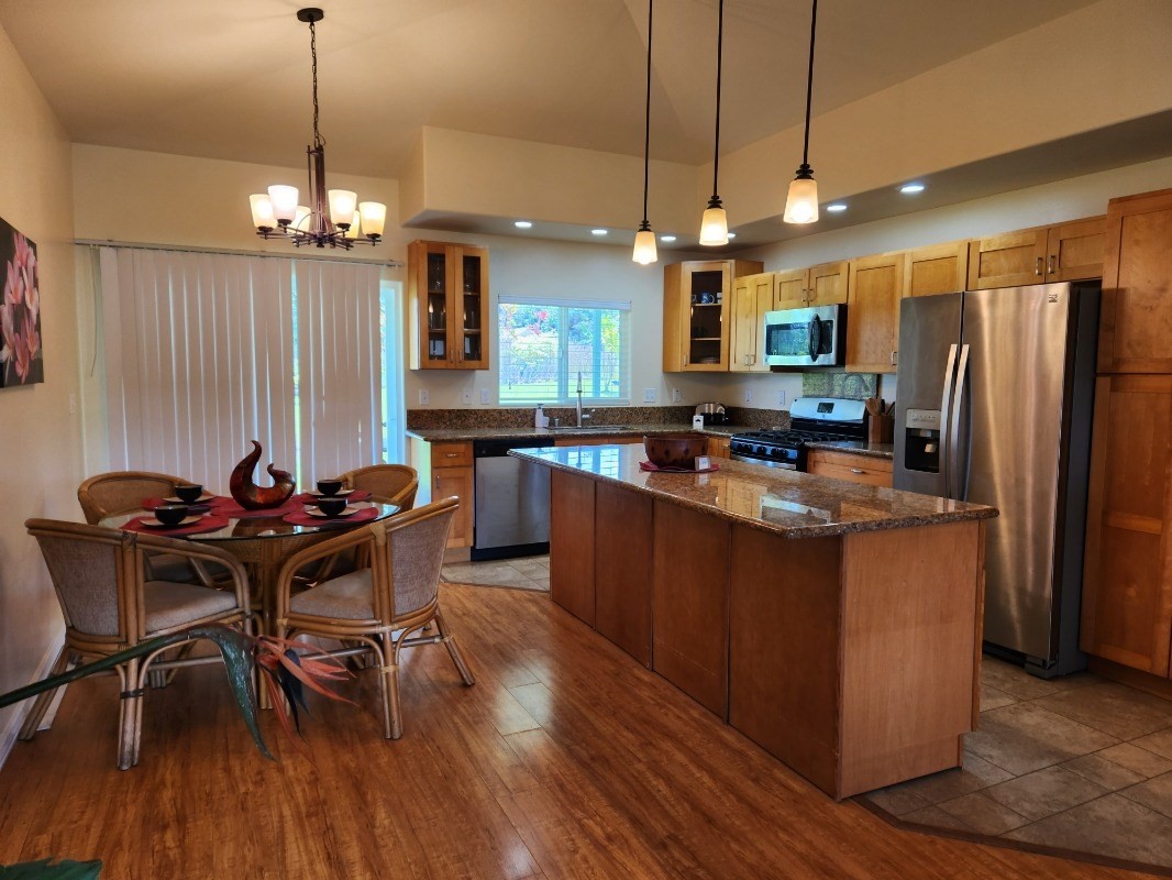 1507 Haleloke Street Hilo, HI 96720 - Photo 11 of 21 a kitchen with stainless steel appliances granite countertop a stove a refrigerator a kitchen island a dining table and chairs