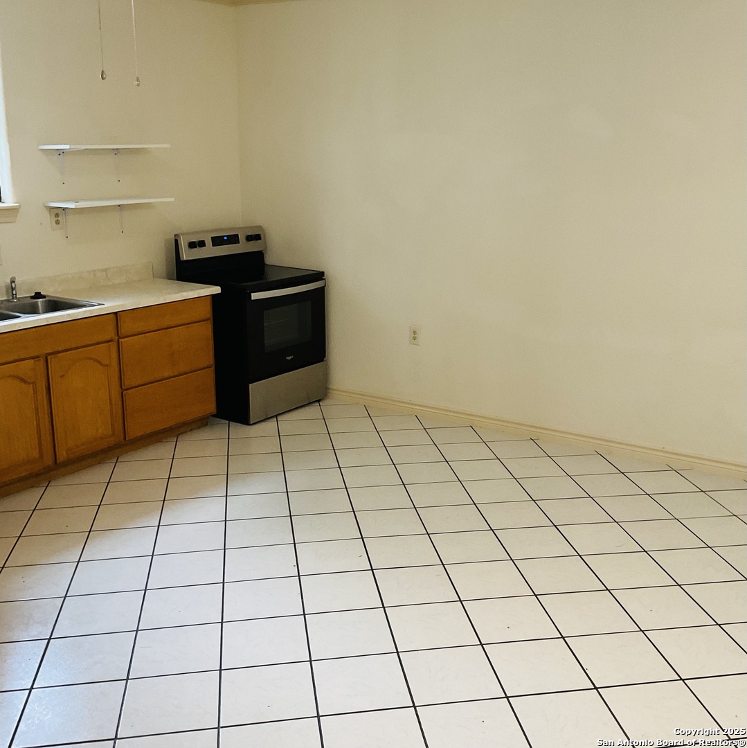 517 West Barnard Sabinal, TX 78881 - Photo 3 of 17 a kitchen with a stove a white cabinet and a shower