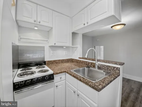 a kitchen with granite countertop a sink stove and cabinets