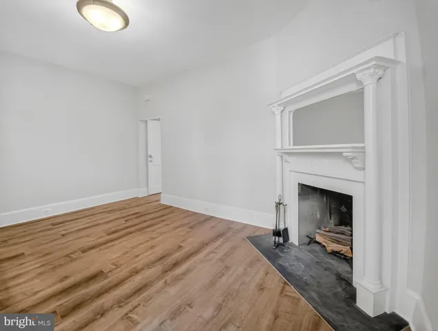 a view of empty room with wooden floor and fireplace