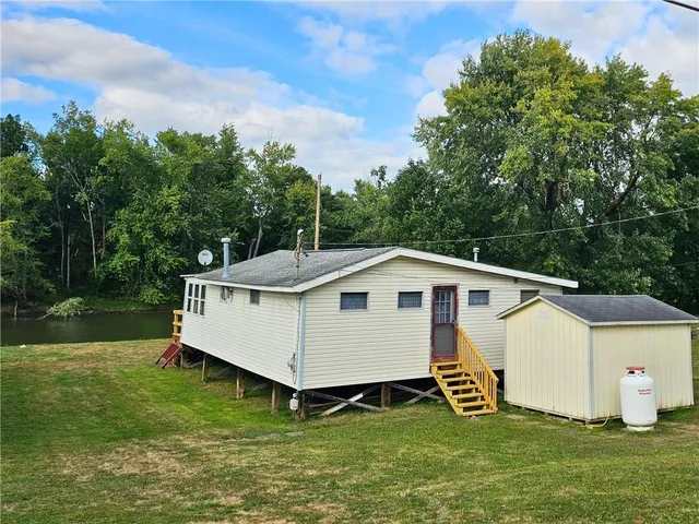 a view of a white house with a yard and sitting area