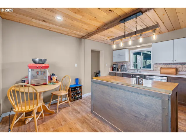 a kitchen with stainless steel appliances granite countertop a sink dishwasher a stove a refrigerator cabinets and a dining table