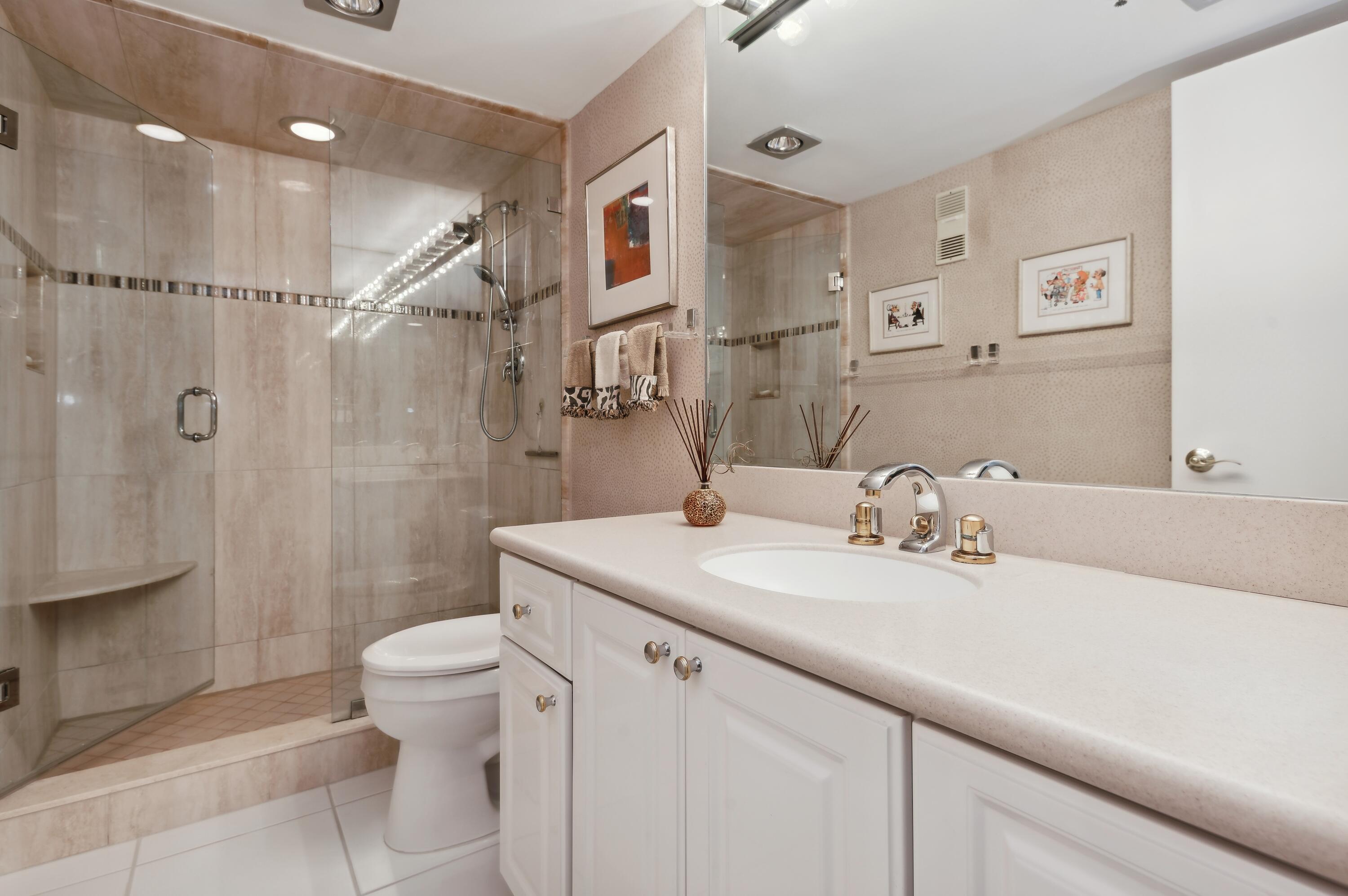 4748 South Ocean Boulevard, Unit 206 Highland Beach, FL 33487 - Photo 19 of 31 a bathroom with a granite countertop sink a toilet a mirror and shower