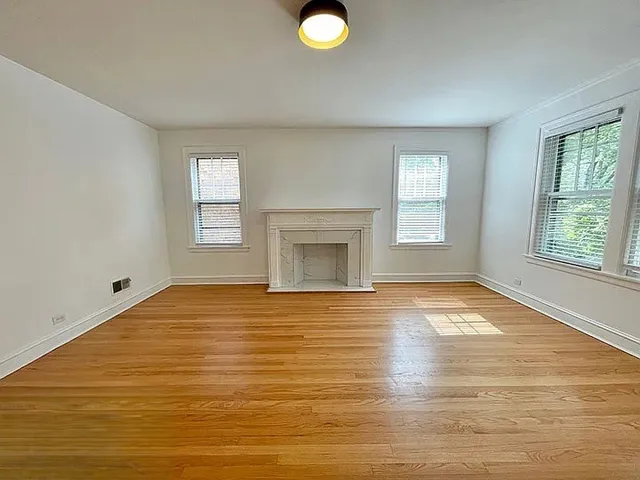 a view of an empty room with a window and fire place