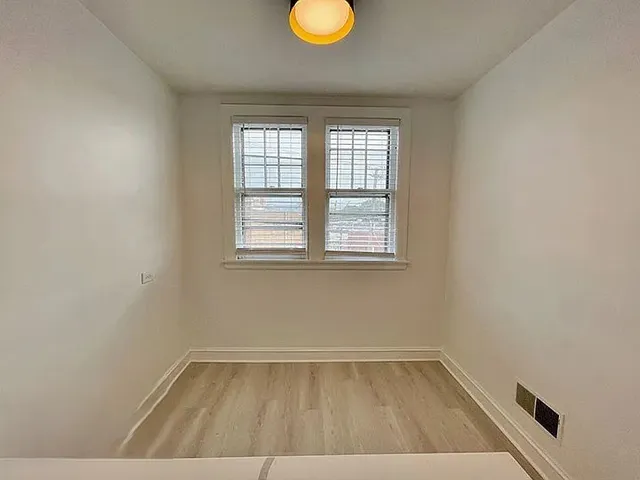 a view of an empty room with window and wooden floor