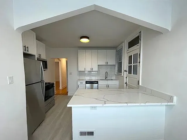 a kitchen with stainless steel appliances granite countertop a sink a refrigerator a stove and a refrigerator with wooden floor