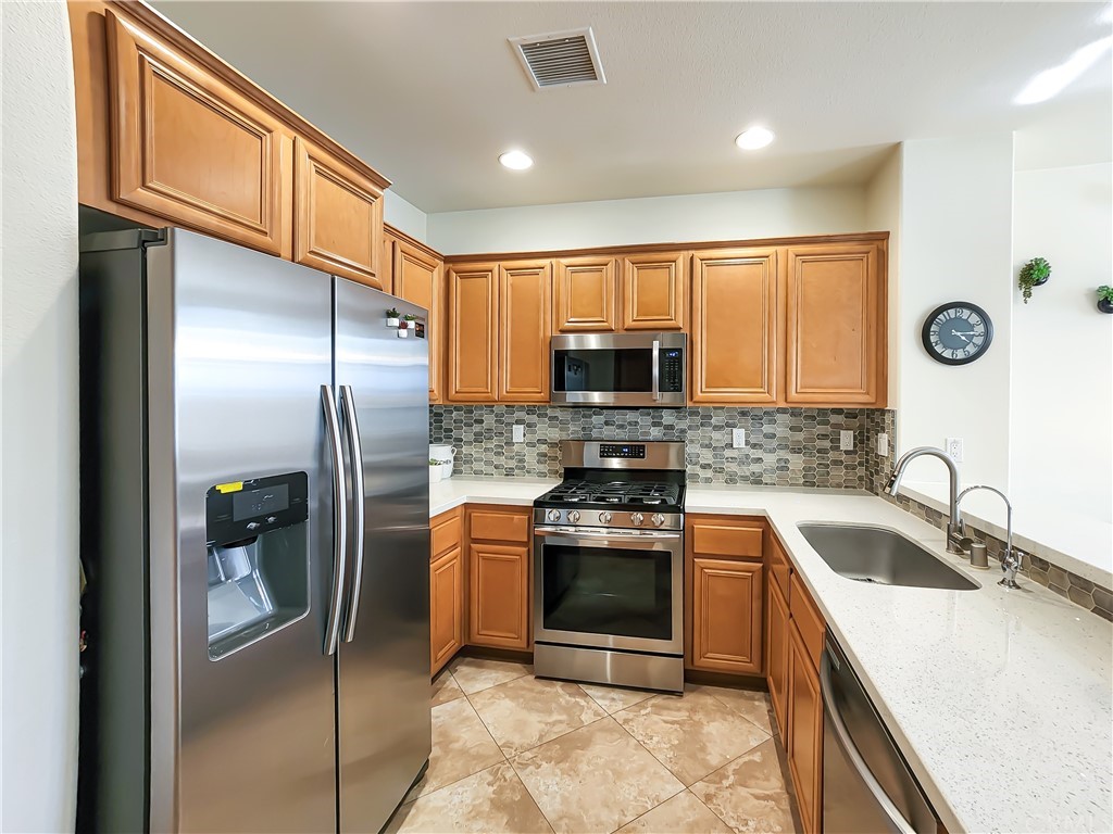 8024 Tulsa Place, Unit 107 Rancho Cucamonga, CA 91730 - Photo 3 of 35 a kitchen with stainless steel appliances granite countertop a sink a stove a refrigerator a washer and dryer