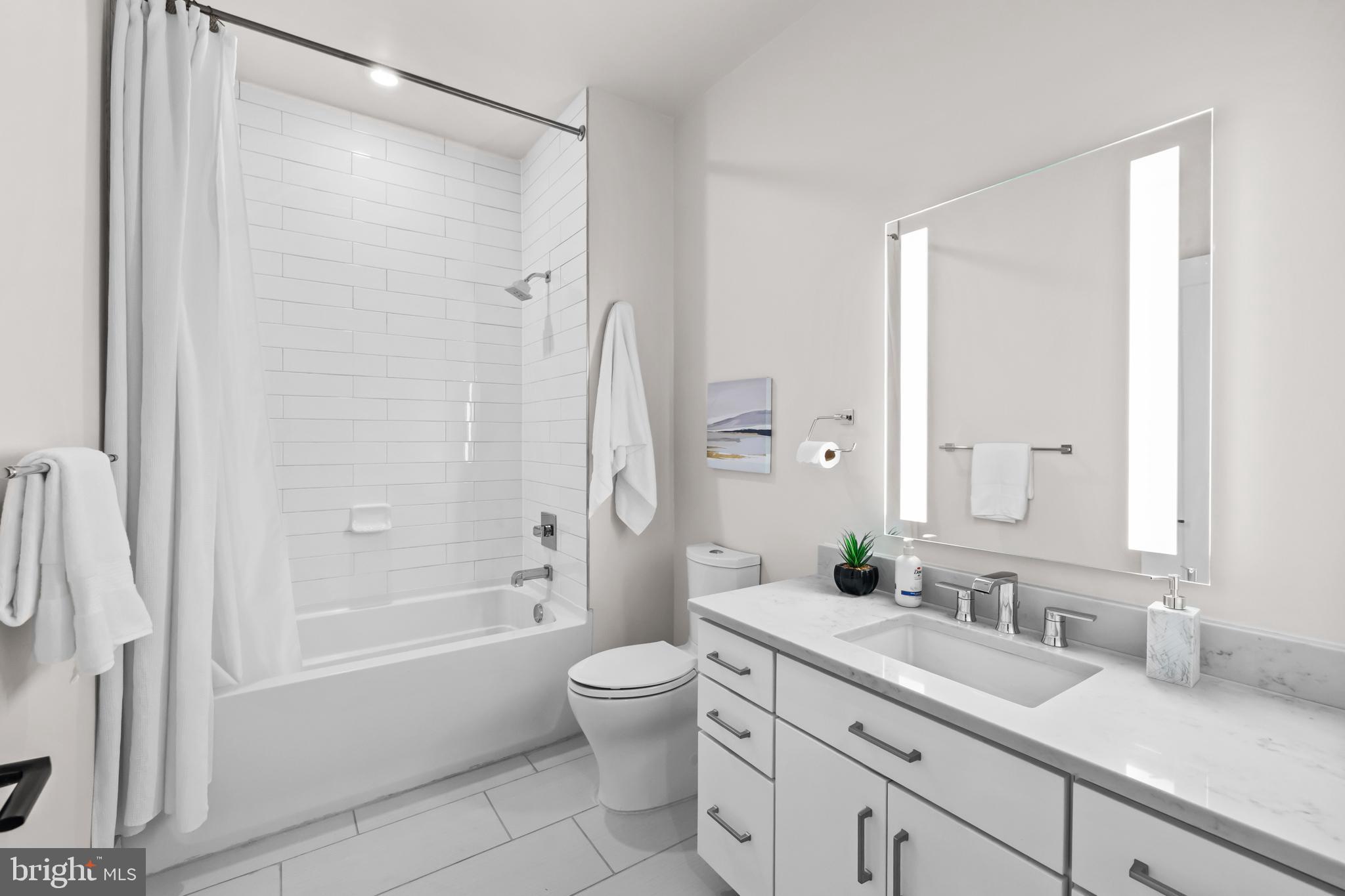 1411 Key Boulevard, Unit 304 Arlington, VA 22209 - Photo 16 of 57 a bathroom with a double vanity sink toilet mirror and bathtub