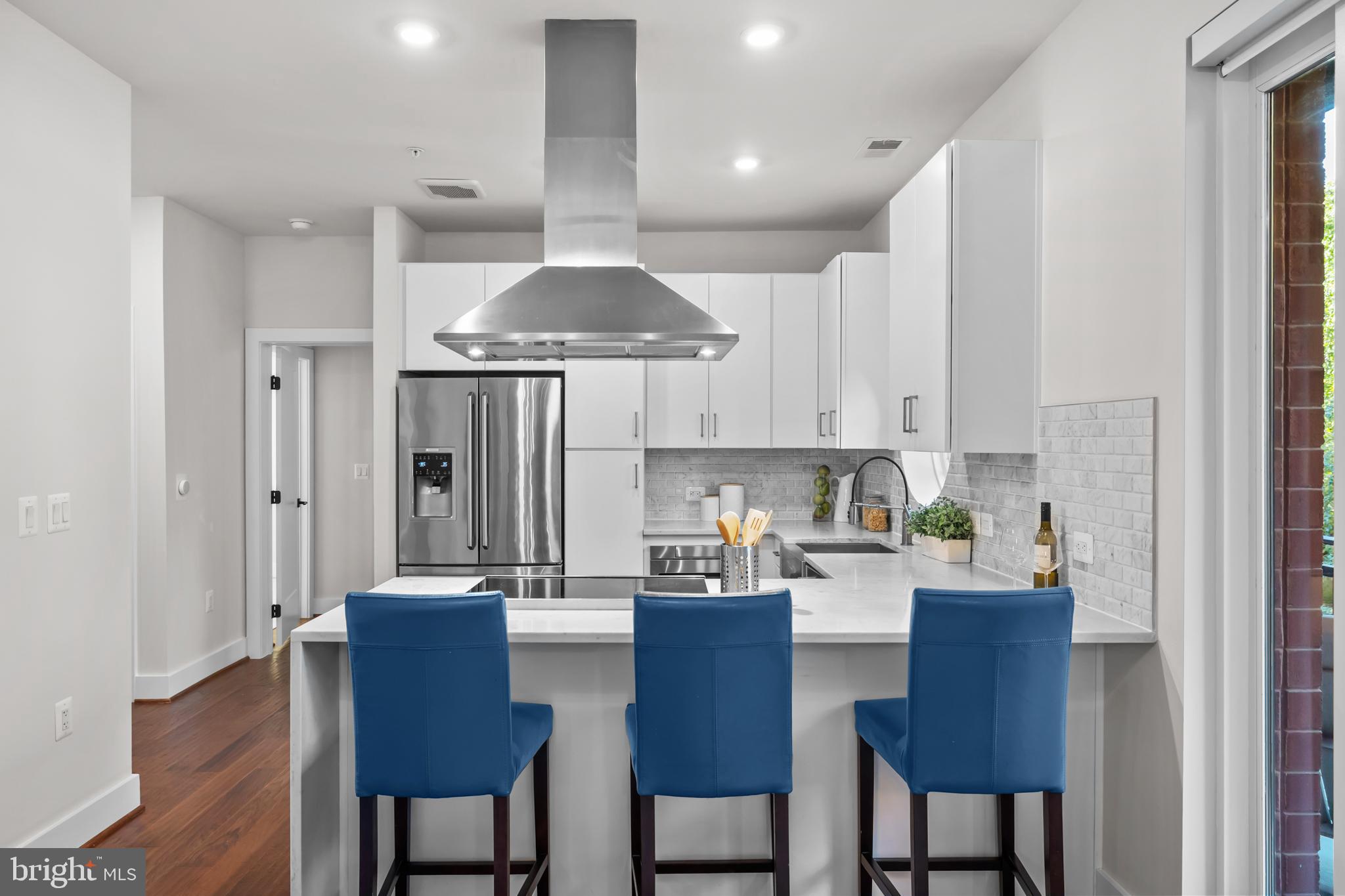1411 Key Boulevard, Unit 304 Arlington, VA 22209 - Photo 7 of 57 a kitchen with stainless steel appliances a sink a stove a refrigerator and white cabinets with wooden floor
