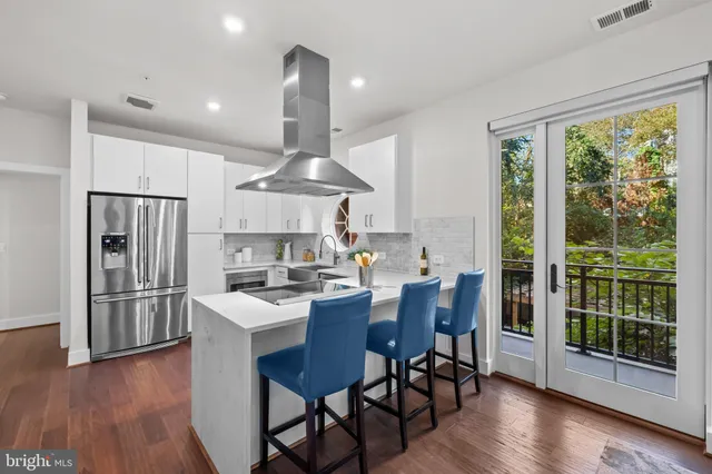 a kitchen with stainless steel appliances a dining table chairs stove and refrigerator