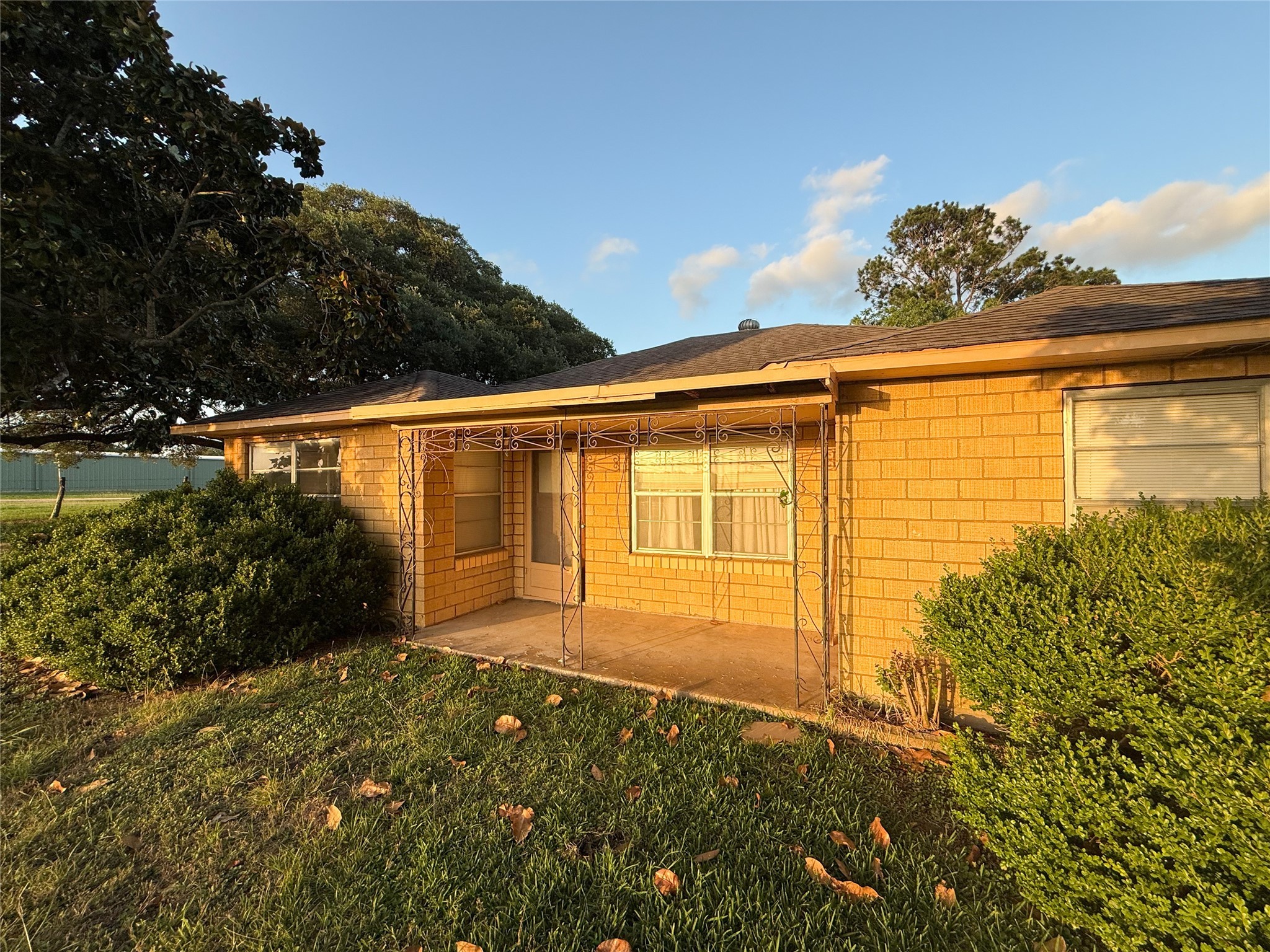 Charming single-story home with a cozy brick exterior, a small covered porch, and manicured bushes. Surrounded by lush greenery, it offers a serene and inviting atmosphere.