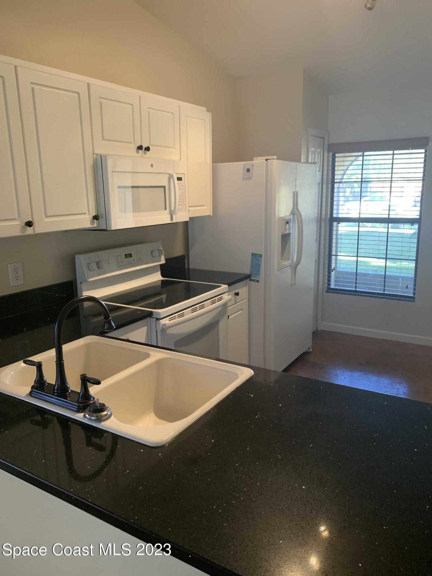 1030 Luminary Circle, Unit 106 Melbourne, FL 32901 - Photo 2 of 14 a kitchen with a sink a refrigerator and cabinets
