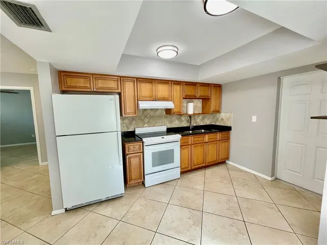 a kitchen with a refrigerator a stove top oven and cabinets