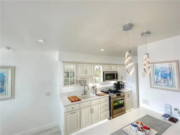 a kitchen with stainless steel appliances granite countertop a stove top oven a sink a dining table and chairs with wooden floor