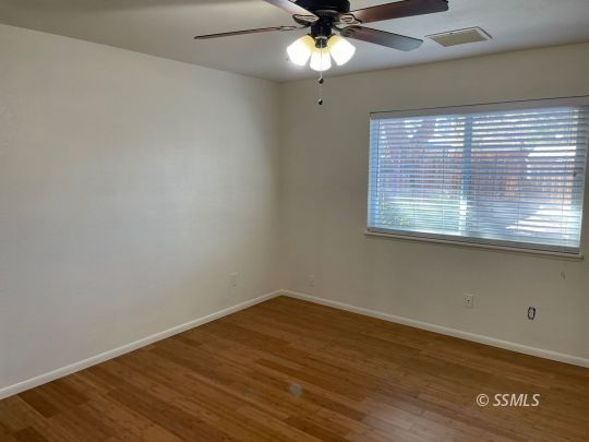 201 Kimberly Lane Ridgecrest, CA 93555 - Photo 7 of 10 an empty room with wooden floor fan and windows