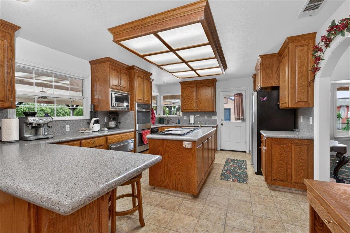 30324 Lone Tree Road Oakdale, CA 95361 - Photo 7 of 74 a kitchen with stainless steel appliances granite countertop a stove top oven a sink dishwasher and cabinets