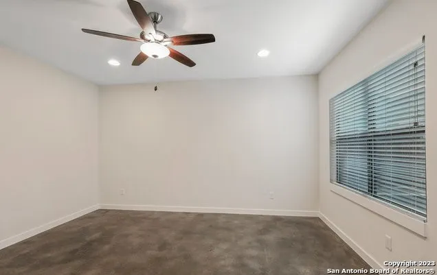 an empty room with a window and a fan