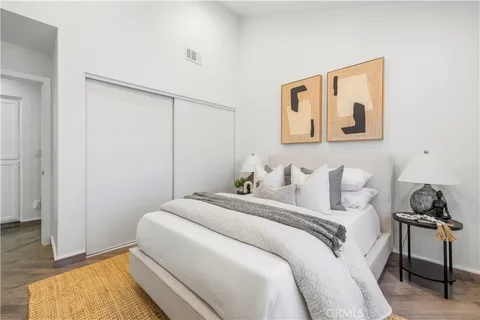 a bedroom with a bed and a potted plant on the dresser