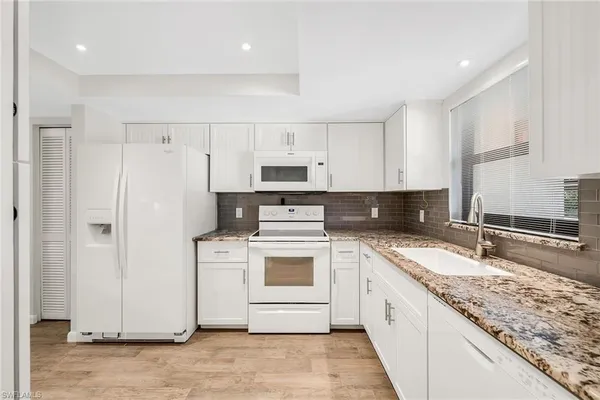 a kitchen with granite countertop white cabinets and white appliances