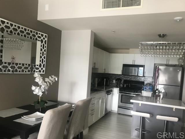 a kitchen with stainless steel appliances kitchen island granite countertop a refrigerator a stove a sink dishwasher and white cabinets with wooden floor