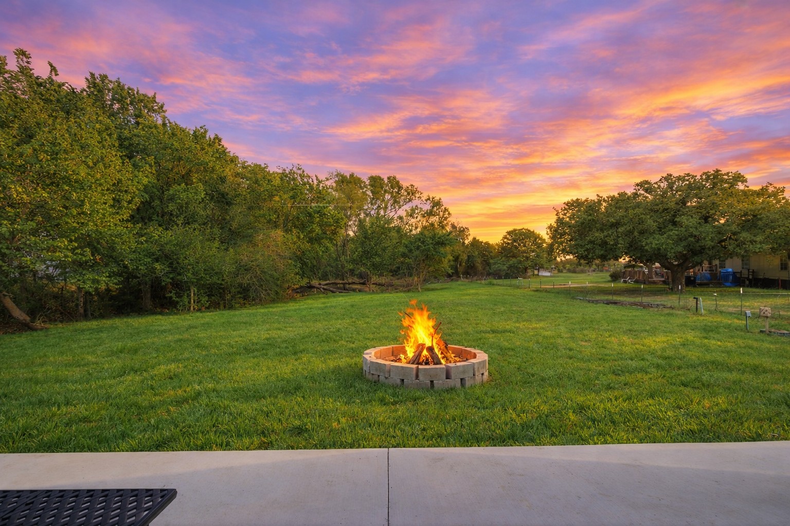 224 Old Coach Lane Elgin, TX 78621 - Photo 6 of 25 The property features an extensive lawn with a fire pit, surrounded by mature trees