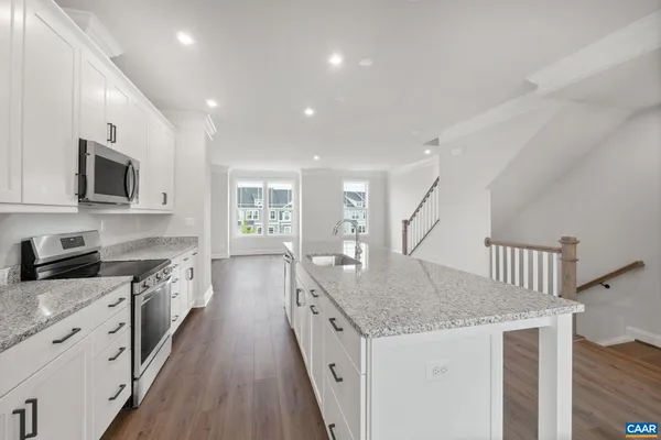 a kitchen with granite countertop a stove top oven a sink a counter space and cabinets