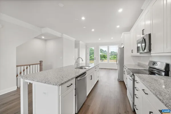 a kitchen with granite countertop a stove a sink a refrigerator and blue cabinets with wooden floor