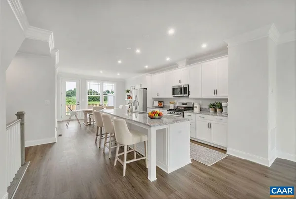 a kitchen with stainless steel appliances a dining table chairs and wooden floor