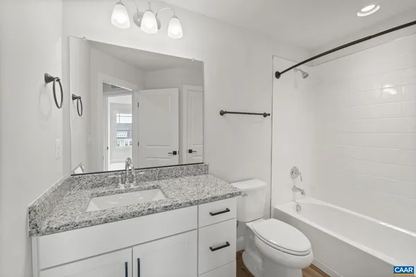 a bathroom with a granite countertop sink a toilet and shower