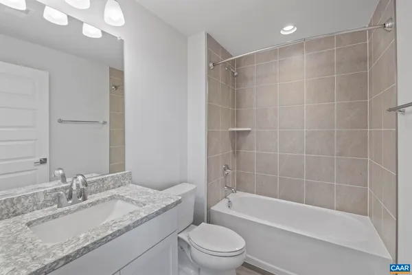 a bathroom with a granite countertop sink a toilet and bathtub