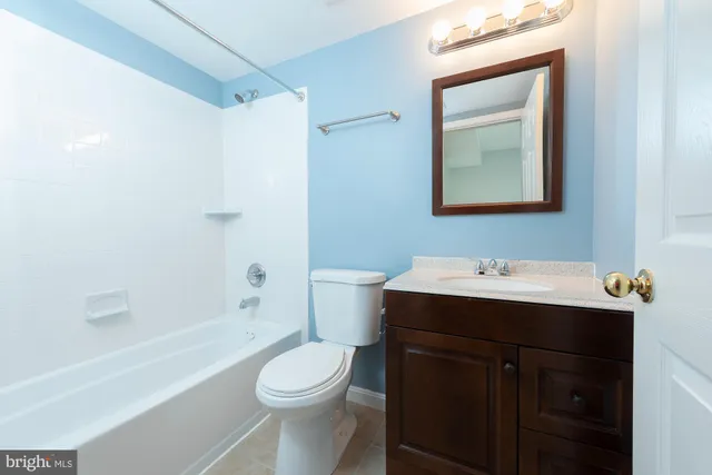 a bathroom with a toilet sink vanity tub and mirror