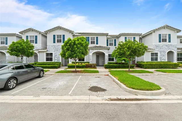 a view of a white house with a yard and plants