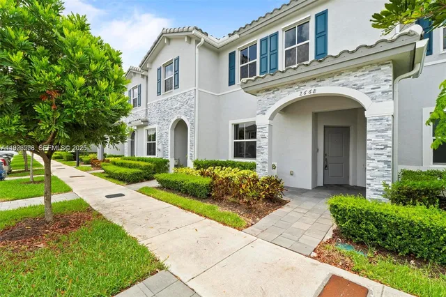 a front view of a house with a garden and plants