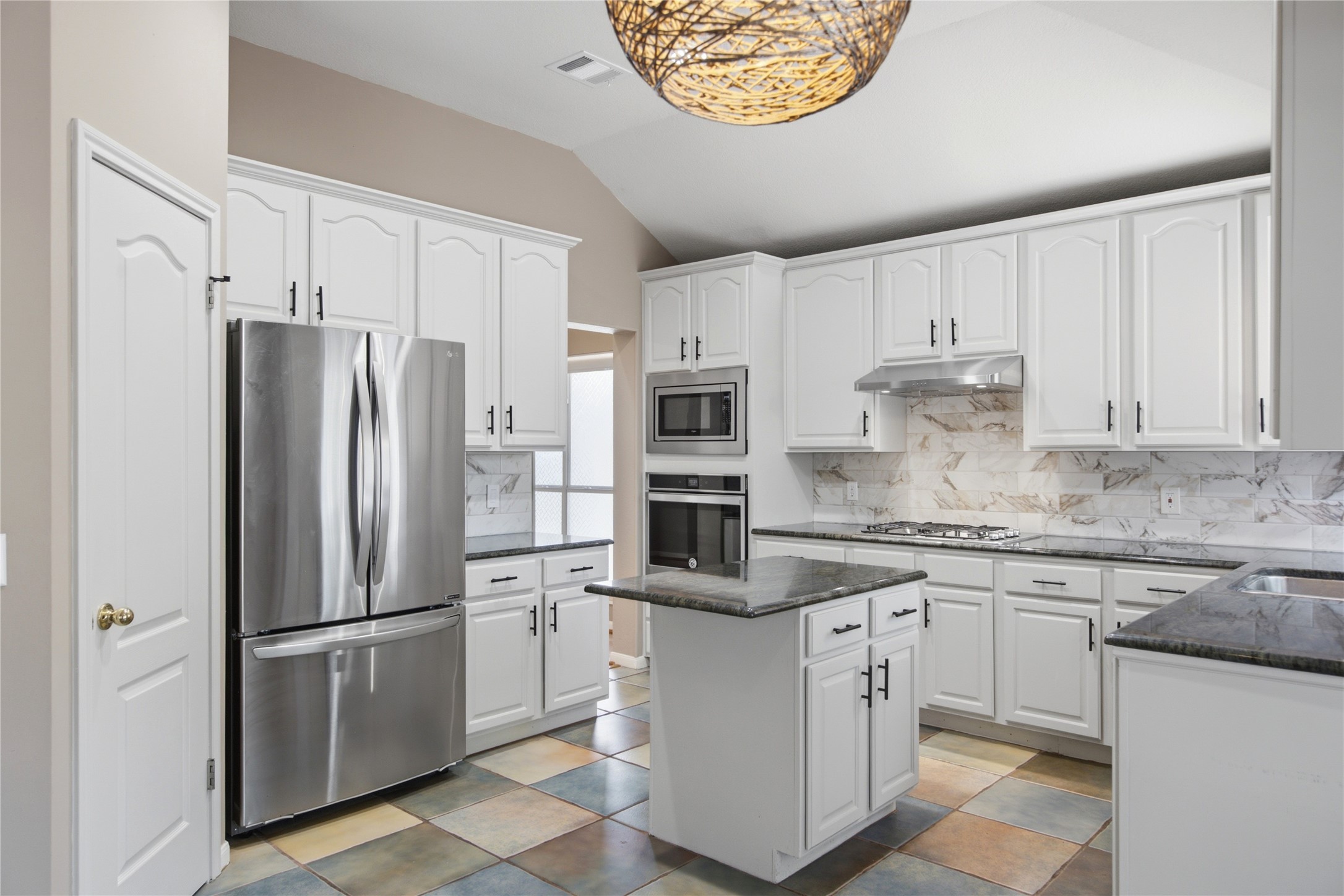 6032 Roxbury Lane Austin, TX 78739 - Photo 17 of 34 Gleaming stone countertops and classic cabinetry anchor this airy kitchen beneath high vaulted ceilings.