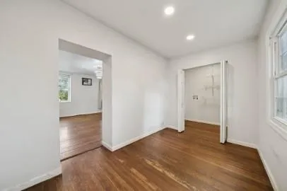 an empty room with wooden floor & windows