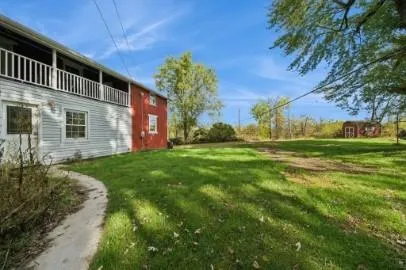a backyard of a house with plants and large tree