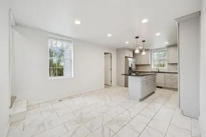 a kitchen with stainless steel appliances kitchen island granite countertop a refrigerator and a sink