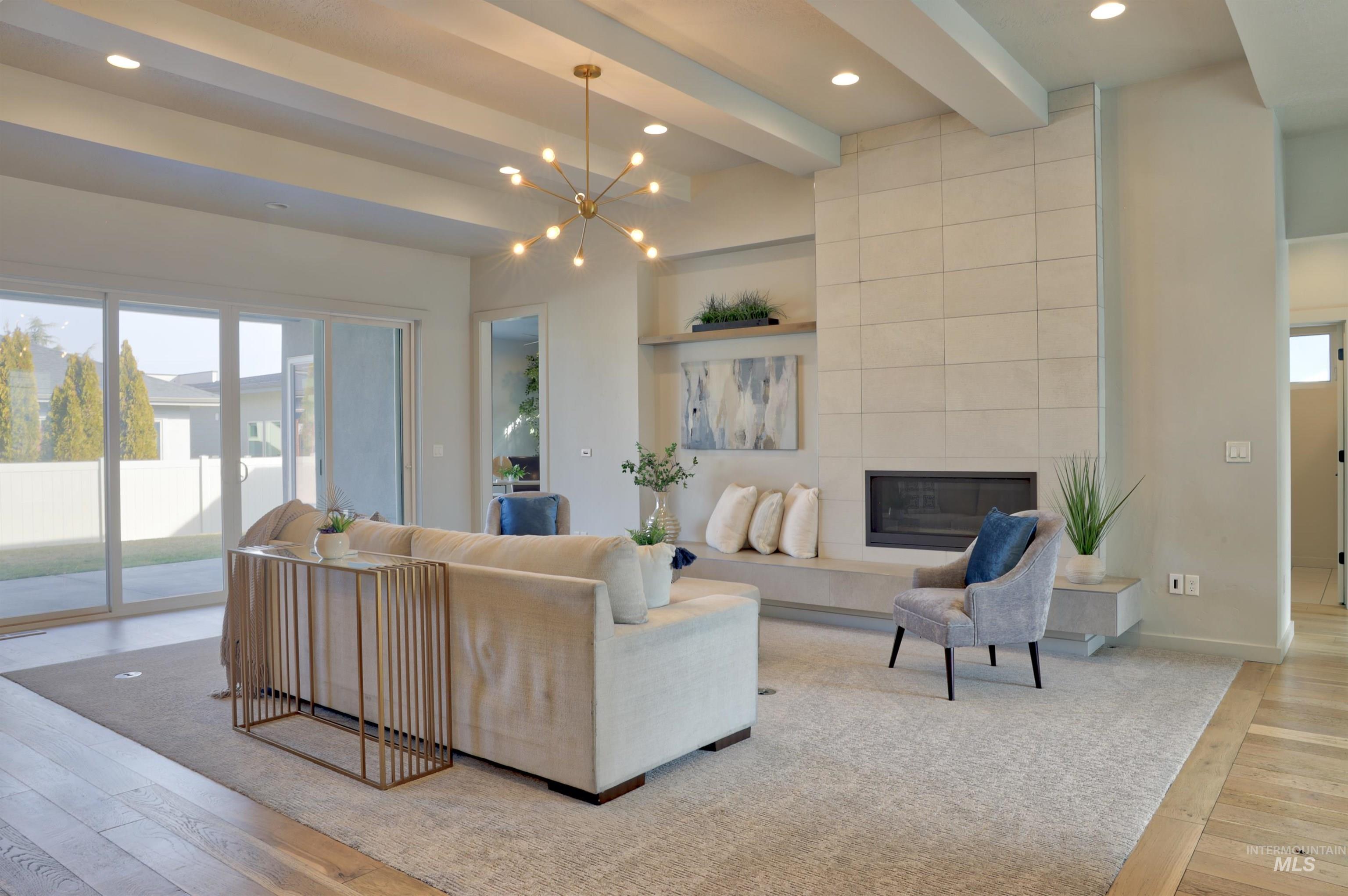 4148 East Copper Point Drive Meridian, ID 83642 - Photo 6 of 26 Living area with light wood-style floors, beamed ceiling, a tile fireplace, and a chandelier