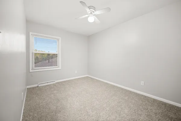 an empty room with a window and ceiling fan