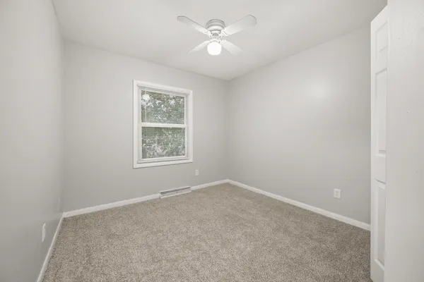 an empty room with a window and a fan