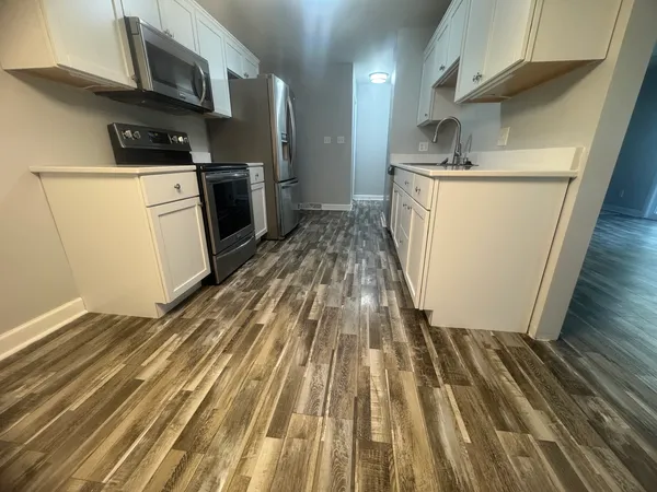 a kitchen with wooden floor and electronic appliances