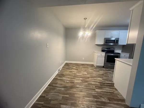 a view of kitchen and empty room with wooden floor